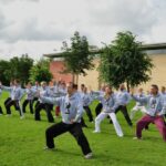 Tai chi class outside beside school.